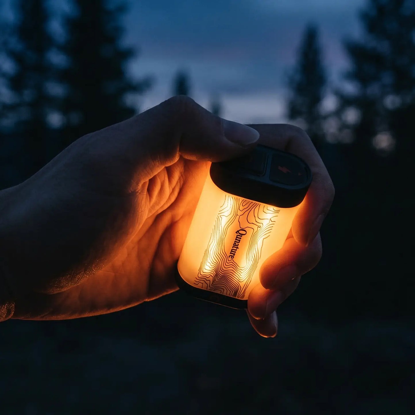 hand drückt taster an schwarzer mini campinglampe im dunklen wald bei abenddämmerung