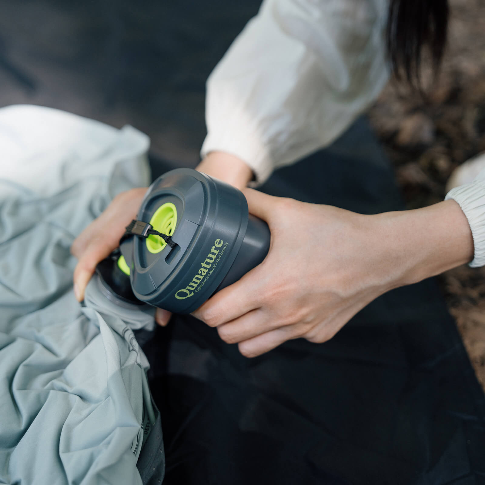 person nutzt mini-luftpumpe zum aufblasen eines schlafsacks im camping