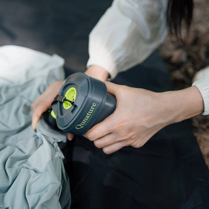 person nutzt mini-luftpumpe zum aufblasen eines schlafsacks im camping