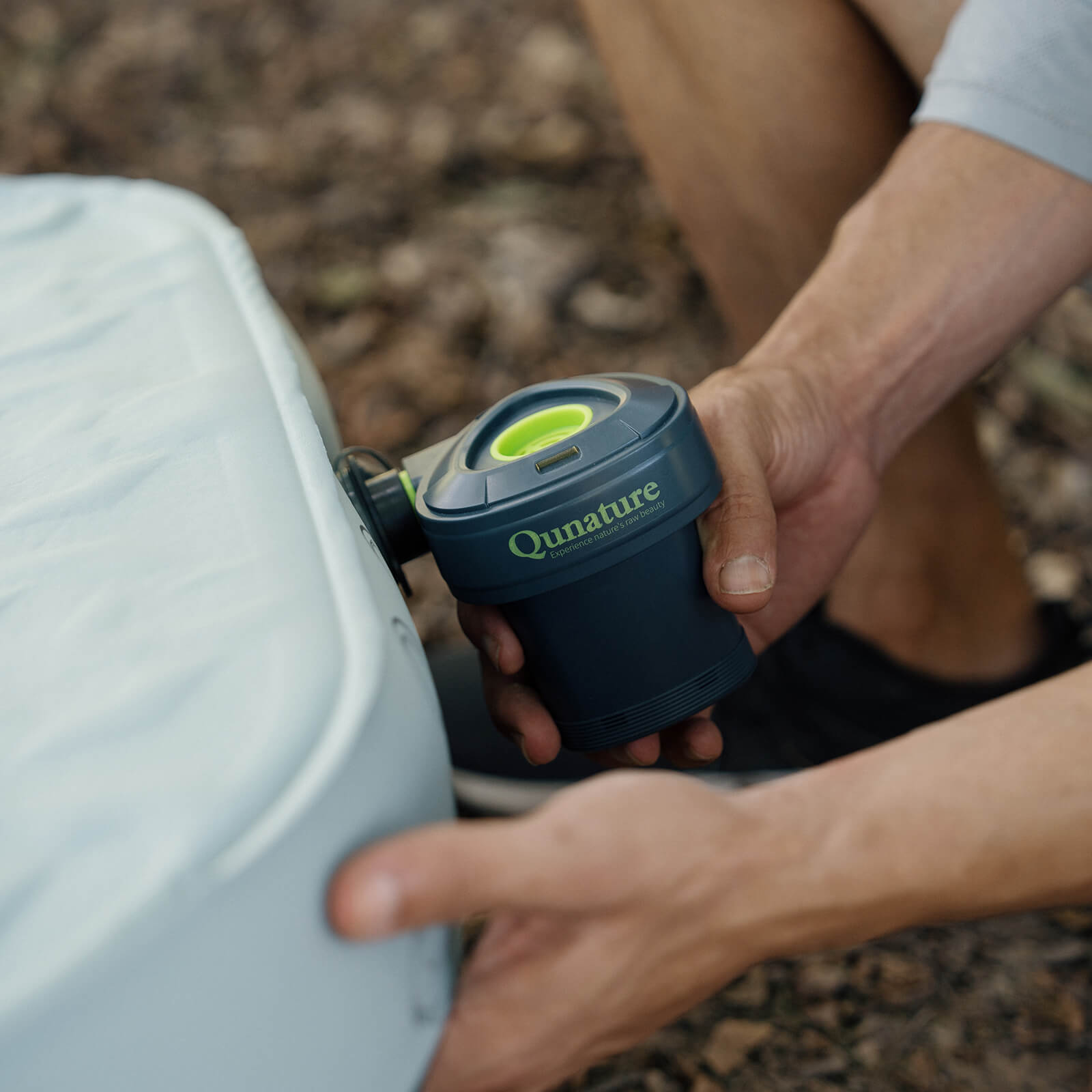 person bedient mini-luftpumpe zum aufblasen einer luftmatratze im freien