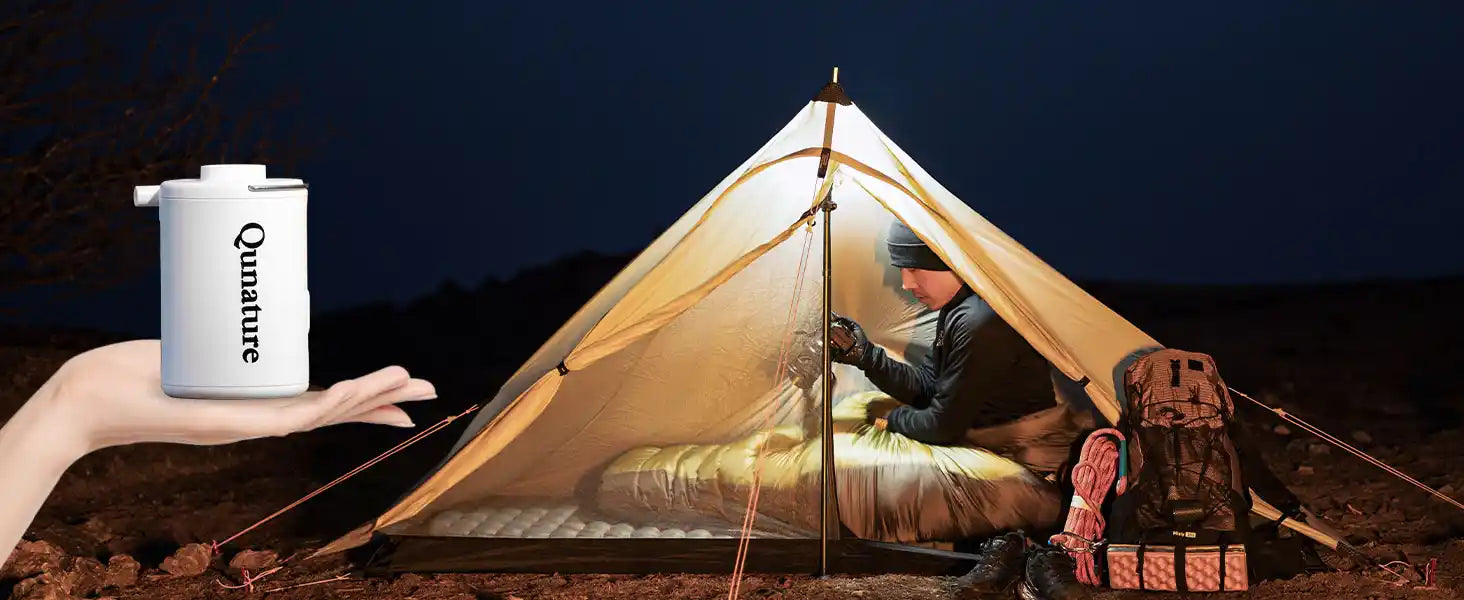 luftpumpe auf einer hand vor einem campingzelt bei nacht