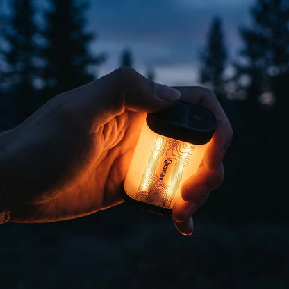 hand drückt taster an schwarzer mini campinglampe im dunklen wald bei abenddämmerung