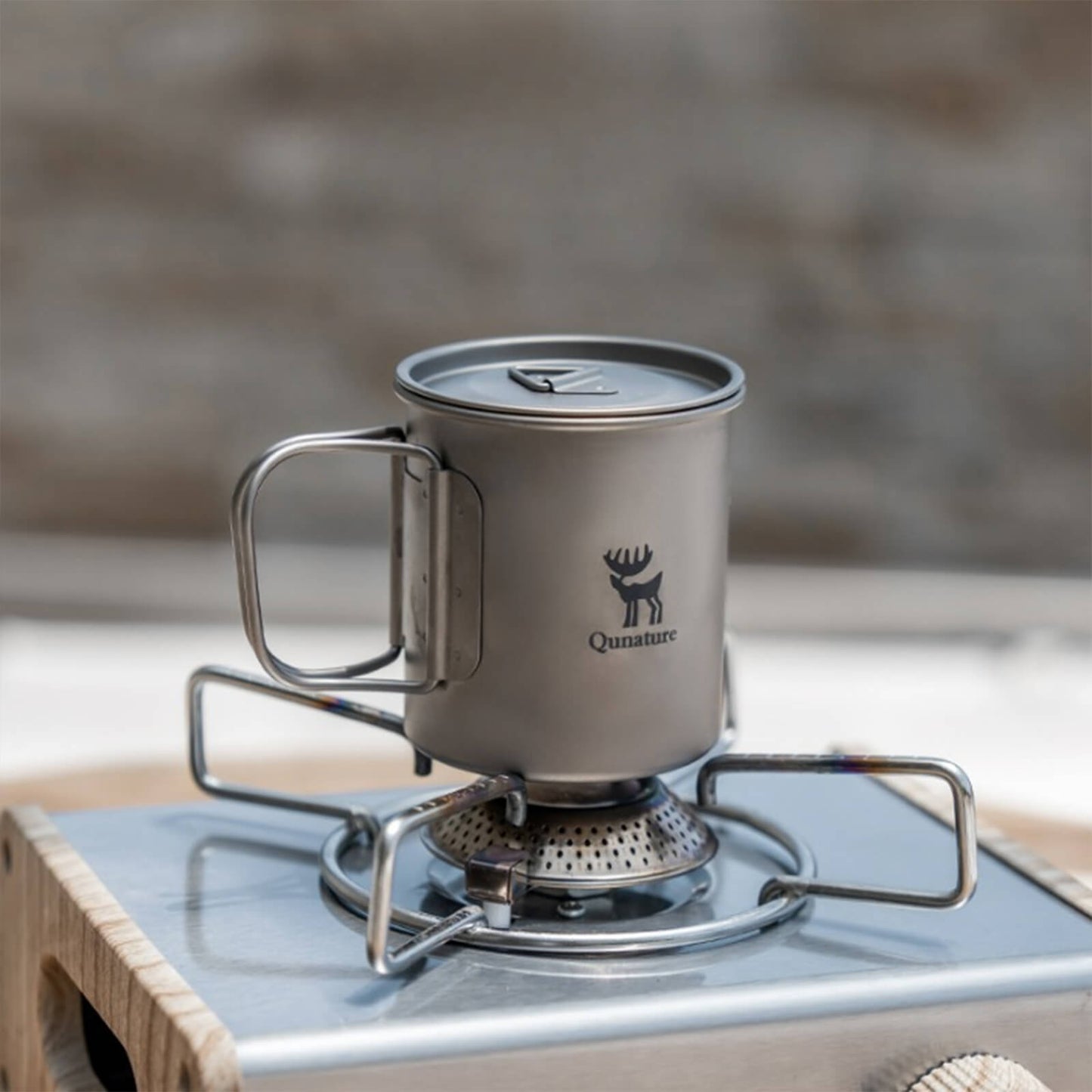 titan camping cup with lid being heated on a gas stove, showing its heat-resistant and cookable feature
